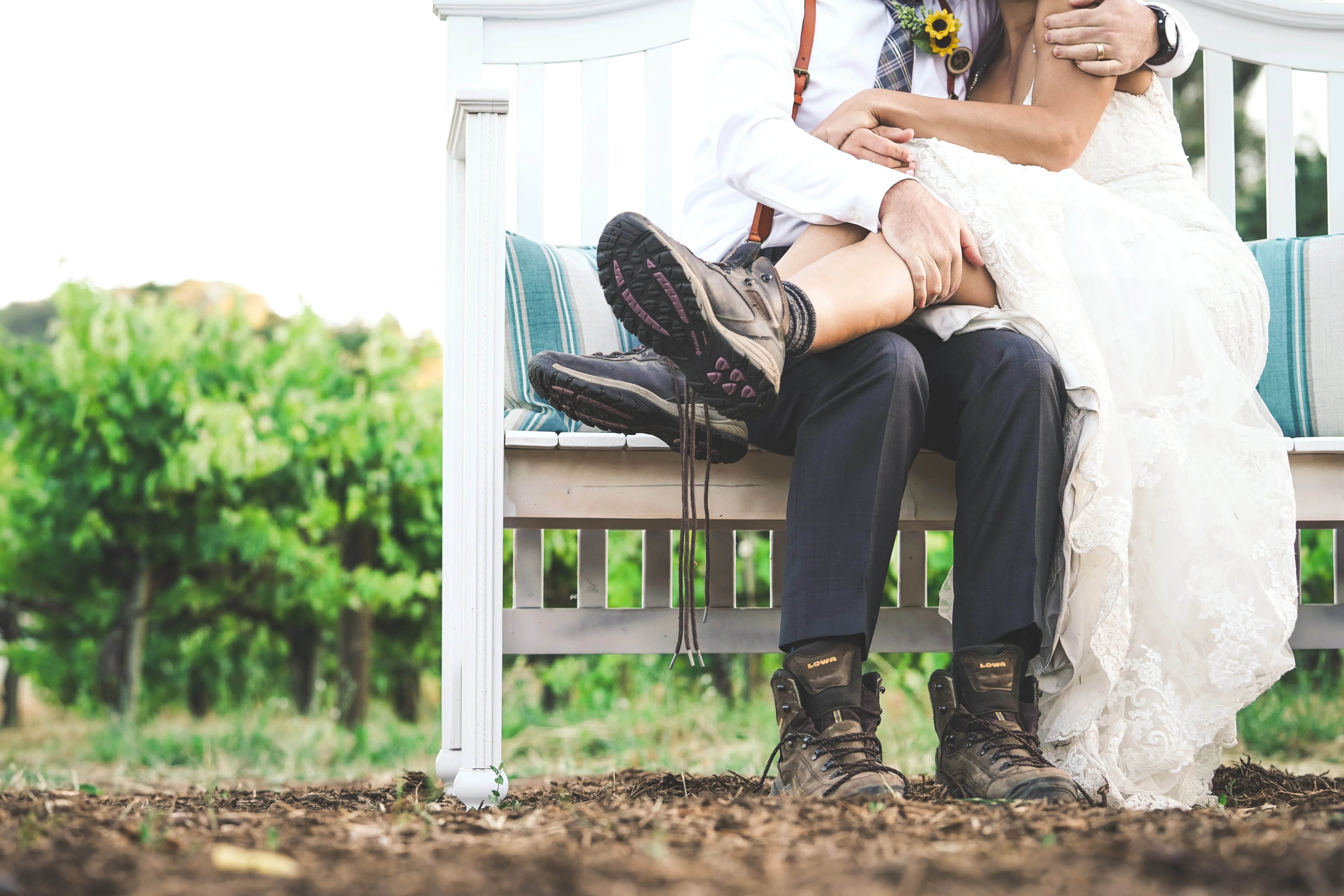 A bride and groom wearing hiking boots sharing a kiss.